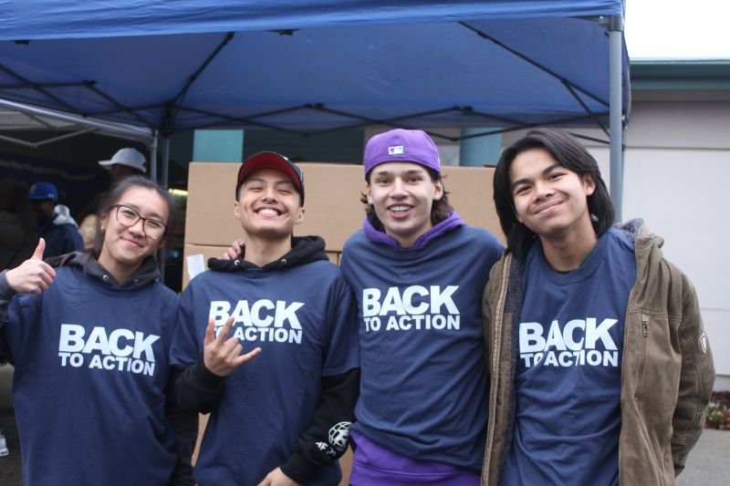Four young volunteers standing wearing matching "Back to Action" shirts celebrating their service.