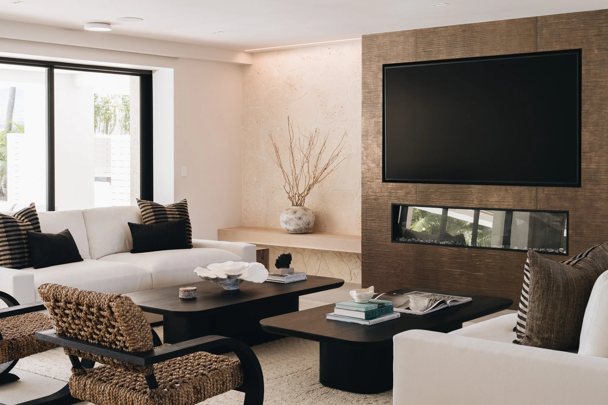 Luxury living room with a fireplace clad in metal resin panel and flanked by freeform coral stone.