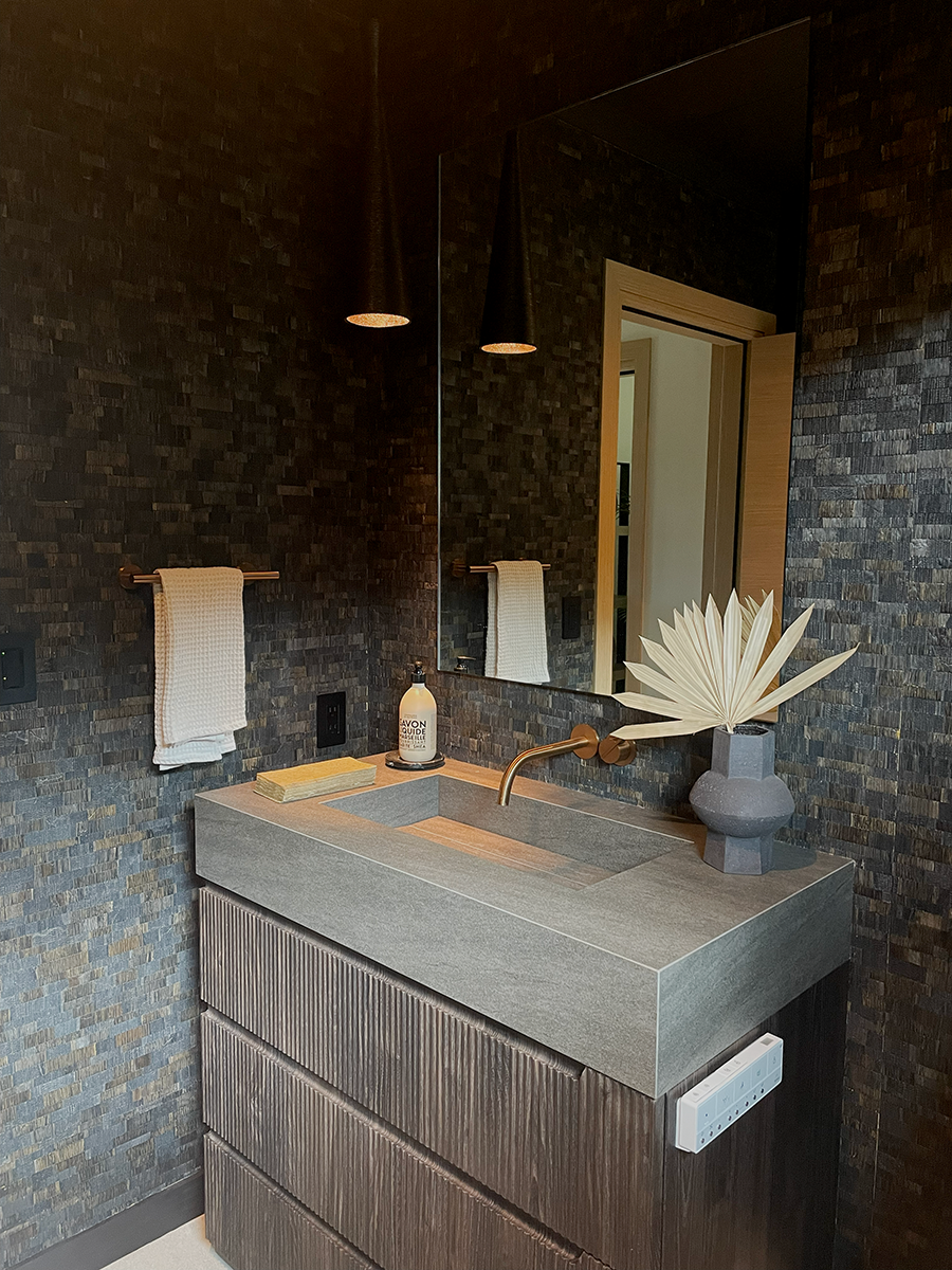 A dark and moody Powder Room with wallpaper and copper fixtures.