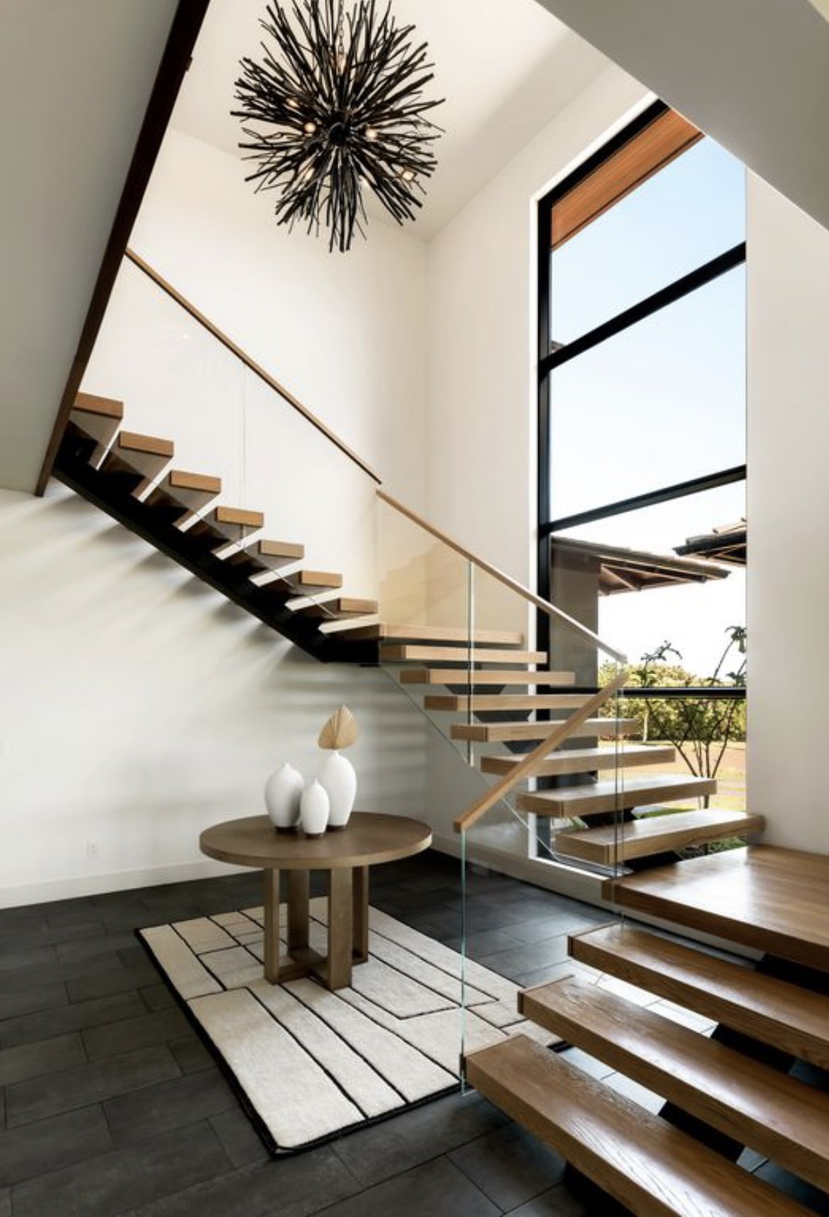 Stairway with centered decorative light fixture in front of a large floor to ceiling window.