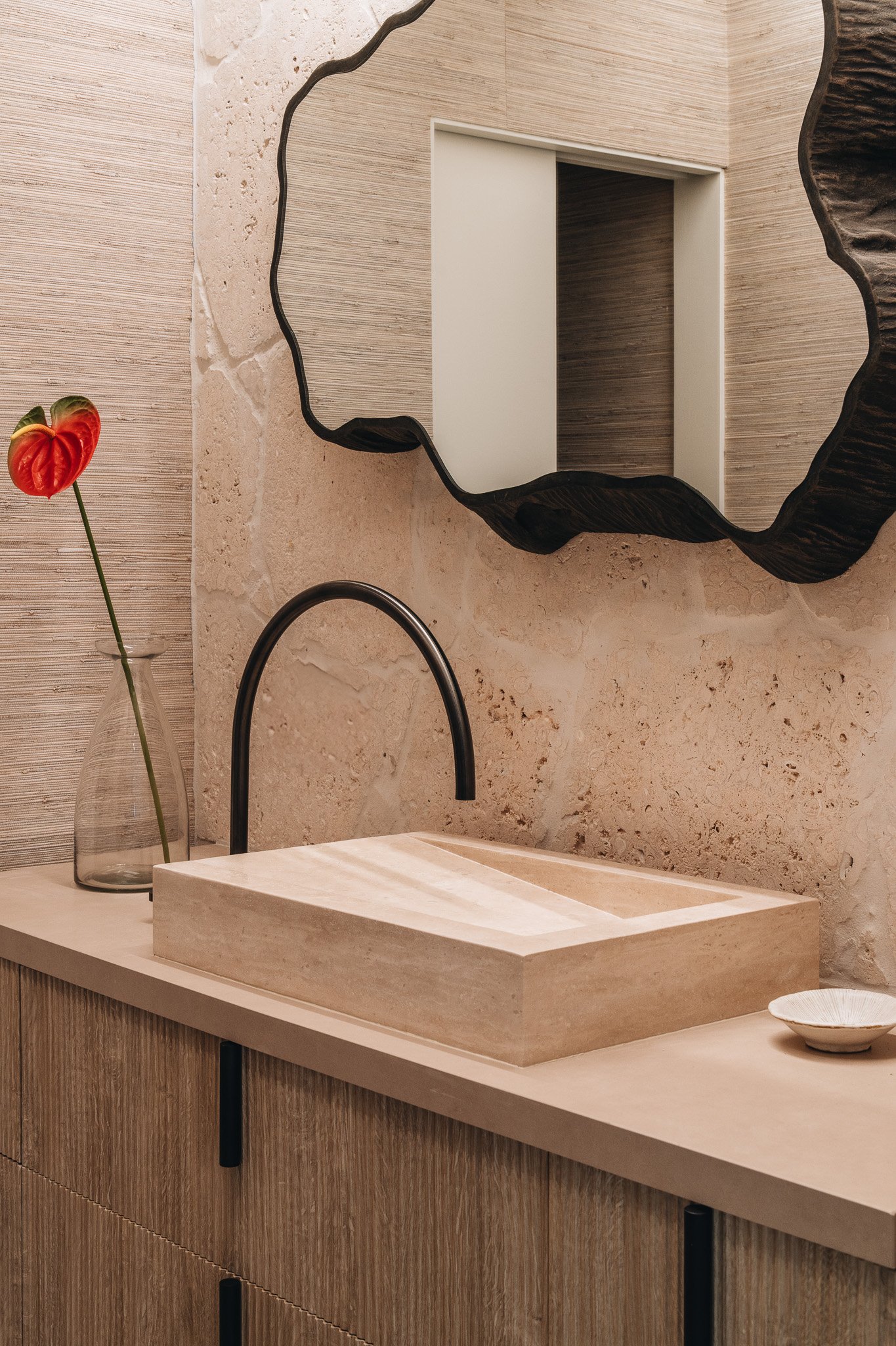 Powder Room vanity with freeform coral stone backsplash and travertine vessel sink.