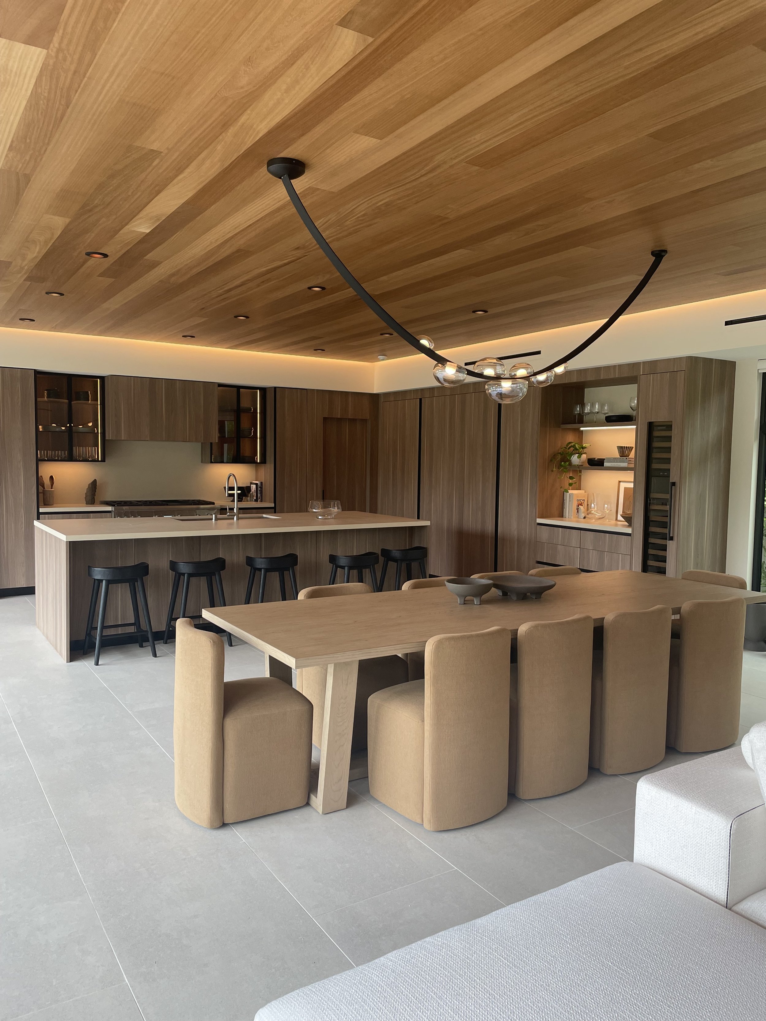 Luxury kitchen designed with medium toned laminate millwork, light stone countertops, and iroko T&G ceilings.