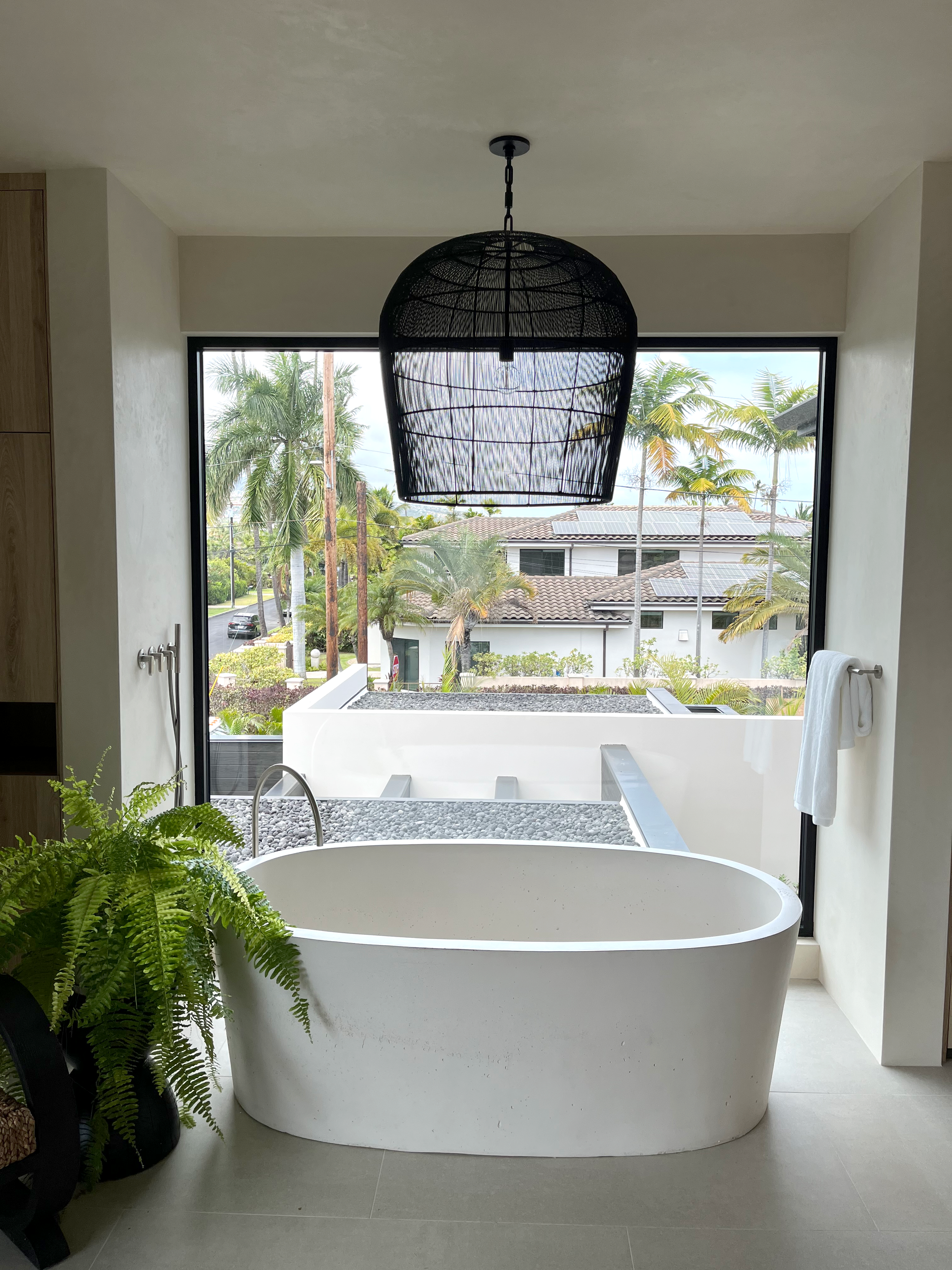Bathtub with large decorative light in front of a window.