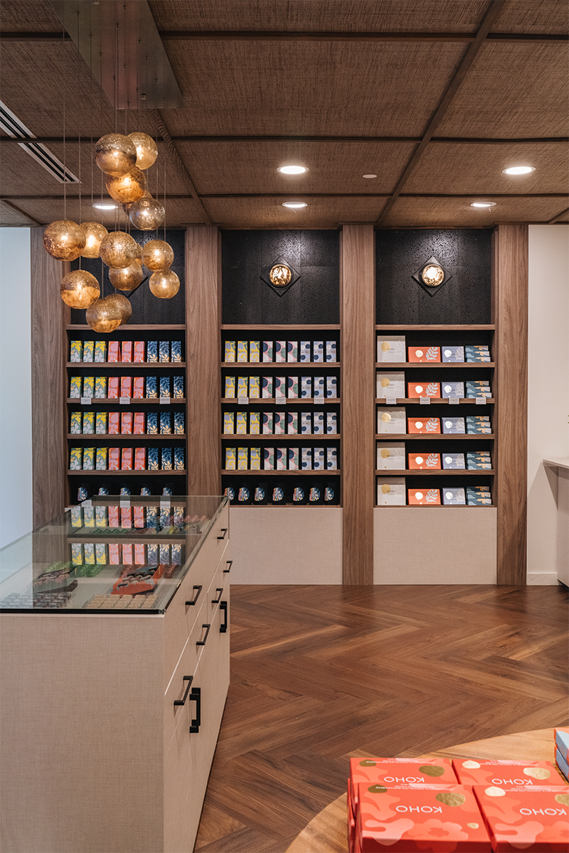 This commercial space highlights Koho's chocolate bars with a wall designed specifically for them. Light fixtures tie into the overall theme of chocolate and bon bons.