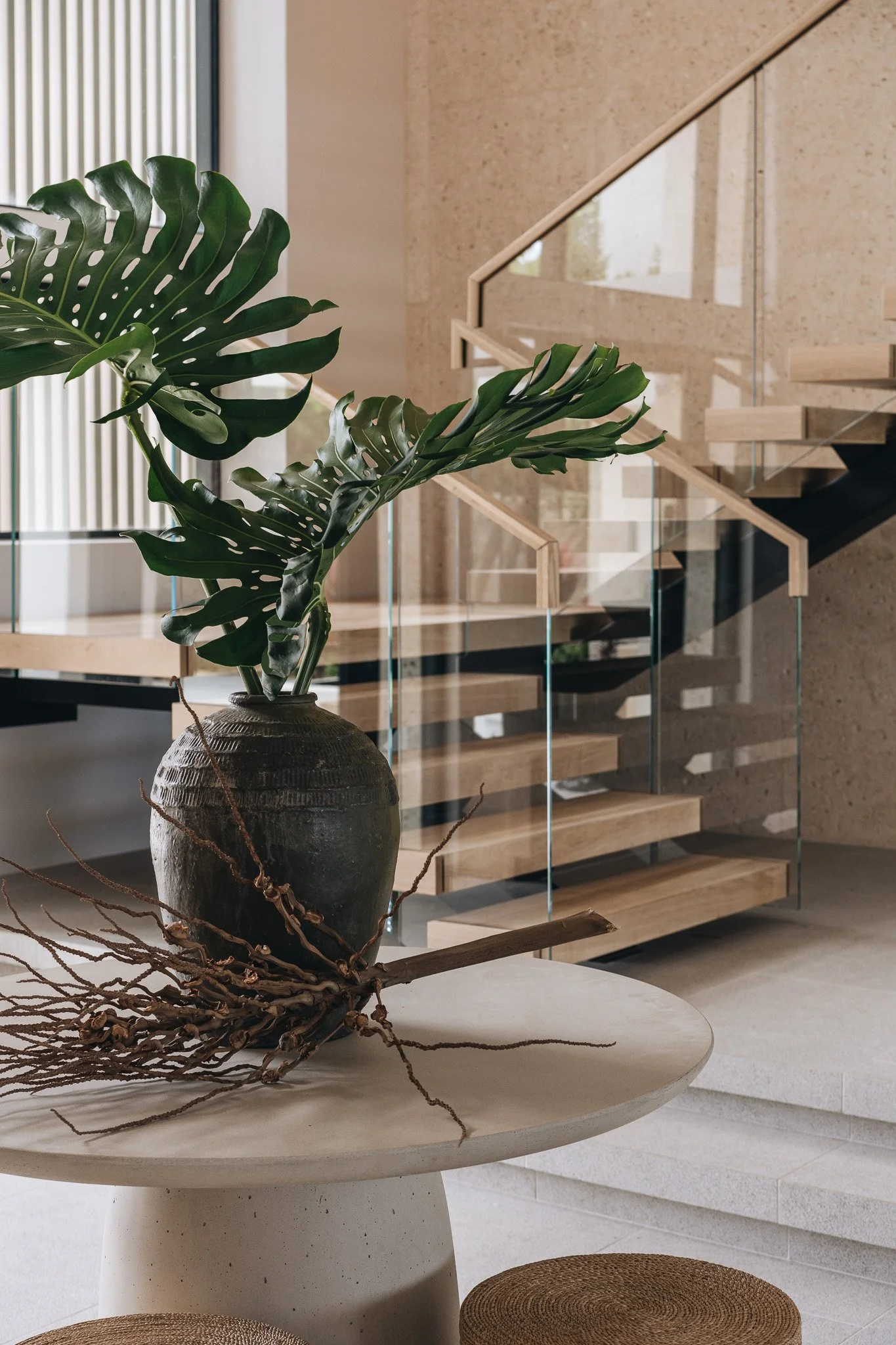 Light oak stairway behind a large monstera plant.