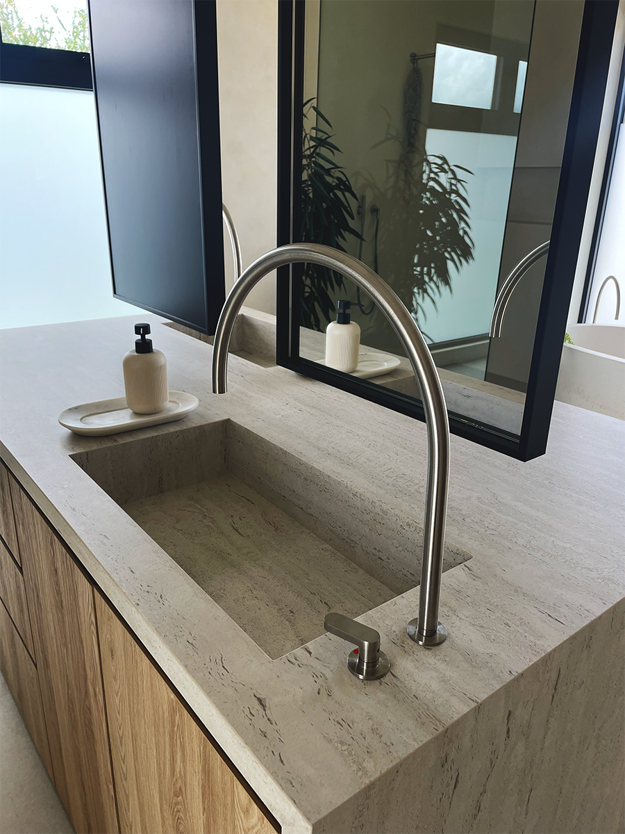 Integrated Dekton sink with a side mounted stainless steel faucet & ceiling hung mirror.