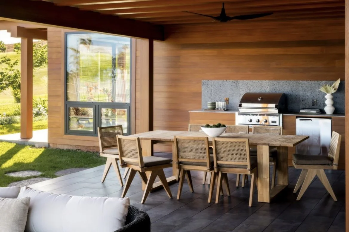Outdoor kitchen with BBQ and puka lava backsplash. The house is clad in a warm midtone wood T&G.