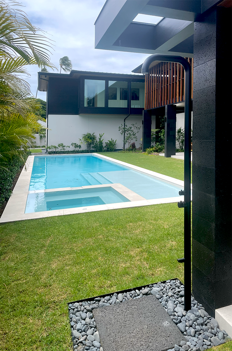 Outdoor shower in front of a pool with a baja ledge.