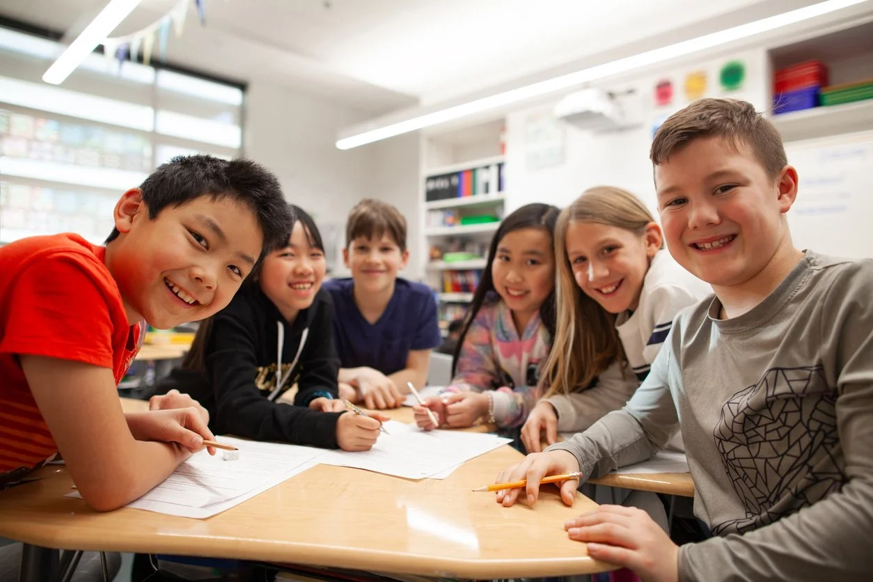 Junior high students sitting together at a desk and smiling during a collaborative maths activity for home‑educated learners in Brisbane.