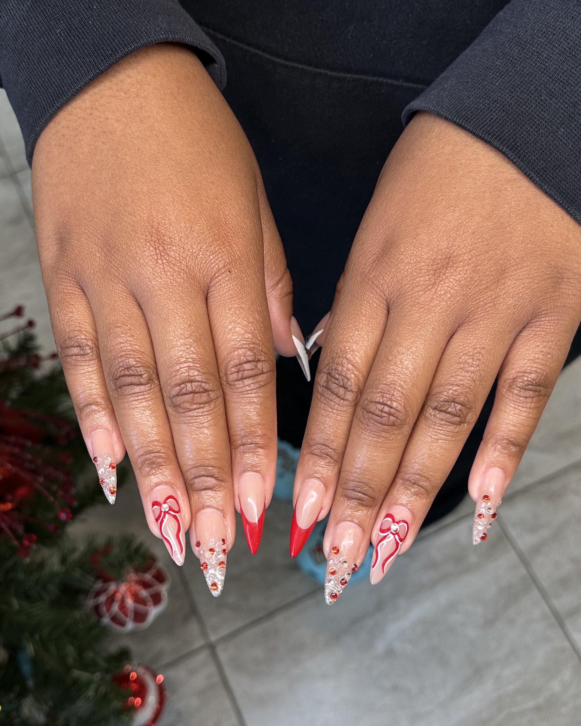 Close-up of a person’s hands with Christmas-themed red and white decorated nails, resting over their lap.