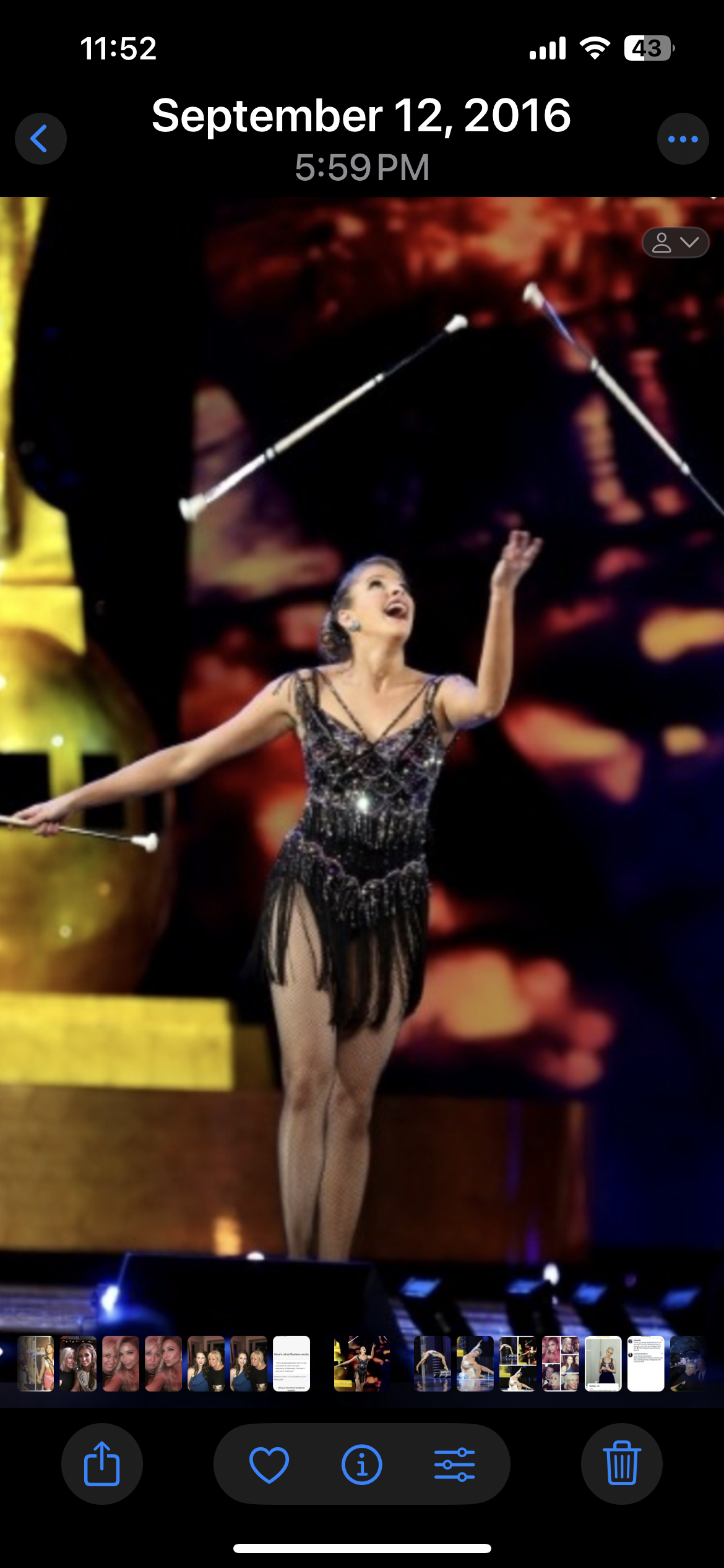 A female circus performer in a black, sparkling costume juggles two clubs on a stage with a colorful backdrop.
