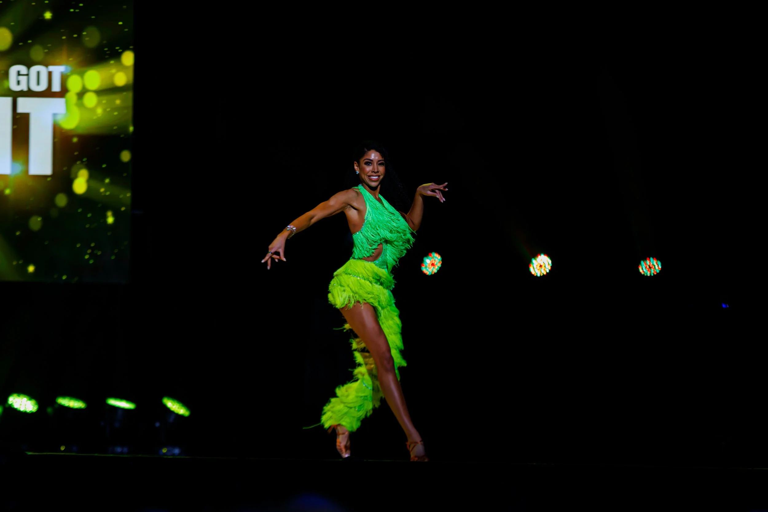 A dancer in a bright green costume performing on stage.