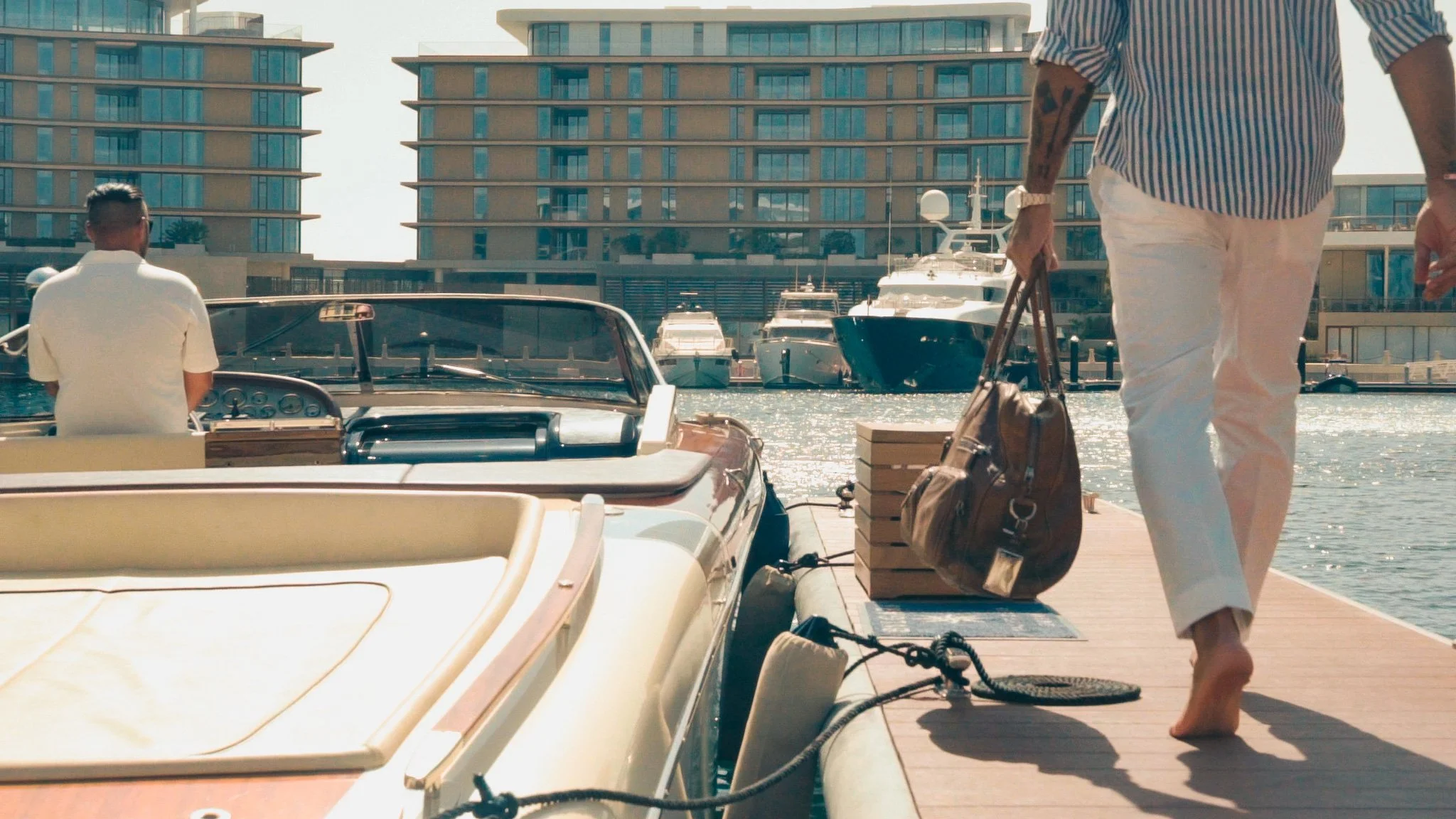 Man carrying bag and walking to a Riva boat on the dock