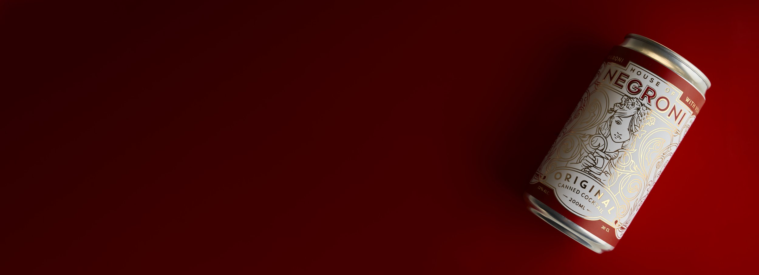 photograph of a can of negroni cocktail lying on a red background
