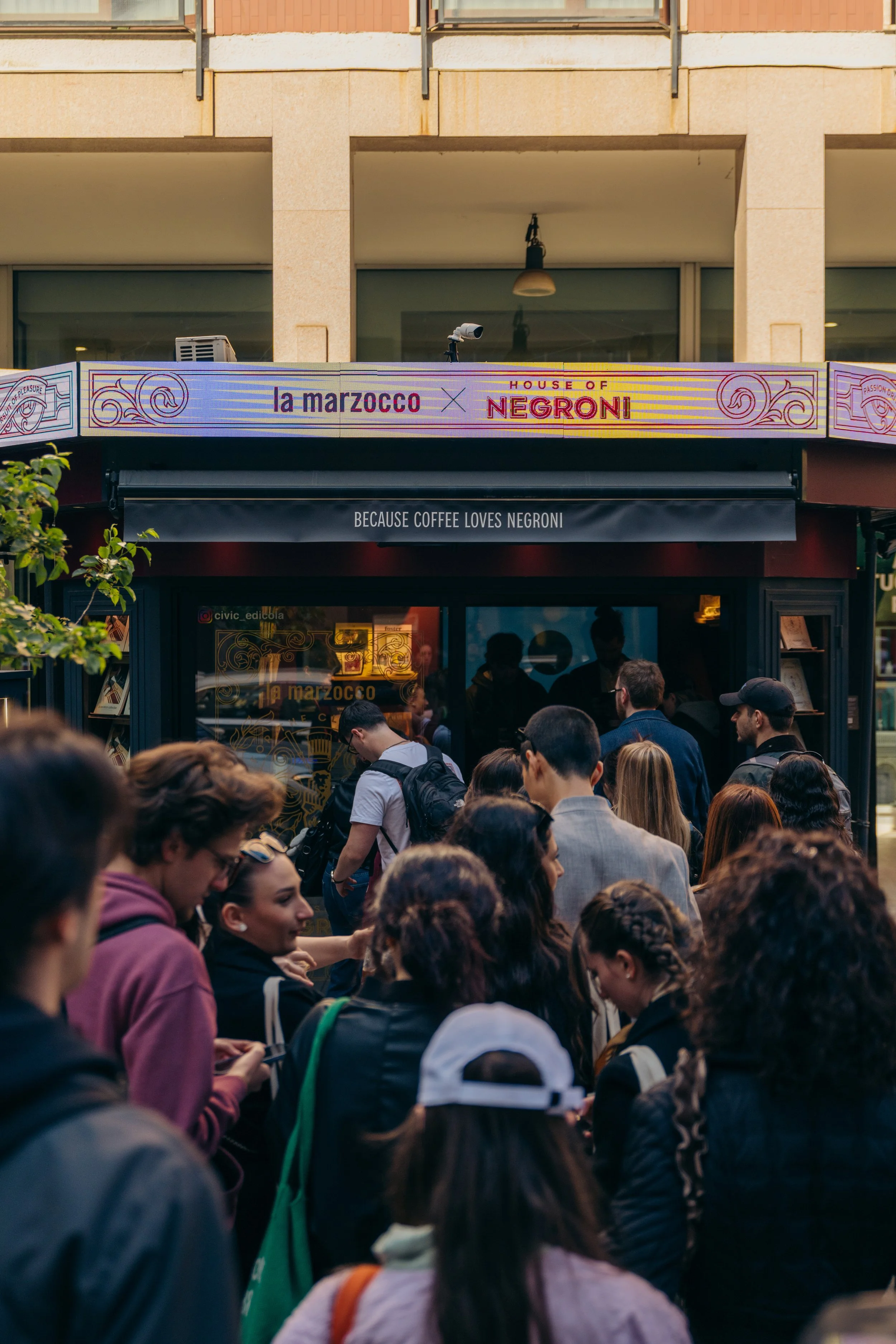 Crowd of people lining up at a newspaper stand in Brera, Milan.