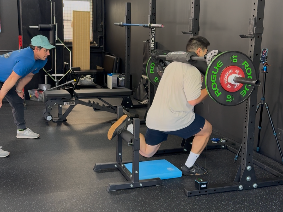 Coaching safety squat bar rear foot elevated split squats using OVR velocity sensor during a performance training session in Seattle, WA.