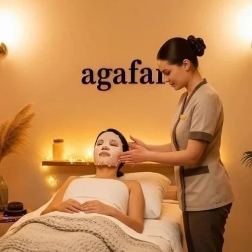 A professional esthetician applying a white sheet mask to a woman’s face during a facial treatment at an Agafar skincare clinic.
