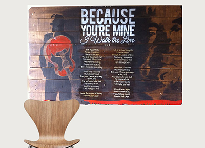 Wall art with a person holding a red balloon and the text 'Because You're Mine I Walk the Line' painted on wooden panels.