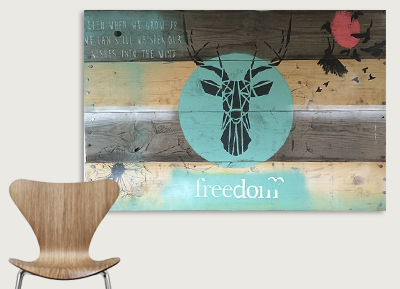 Decorative wall art with a stylized black deer head inside a light blue circle, on a rustic wooden background, with the word 'freedom' and red and black floral accents above.