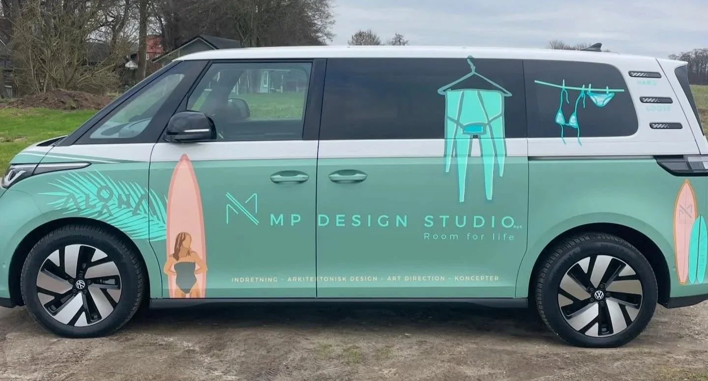 En bil med design fra MP Design Studio, der viser surfebåde, en kvinde i badetøj, en heg, og tøj hængende til tørring.
