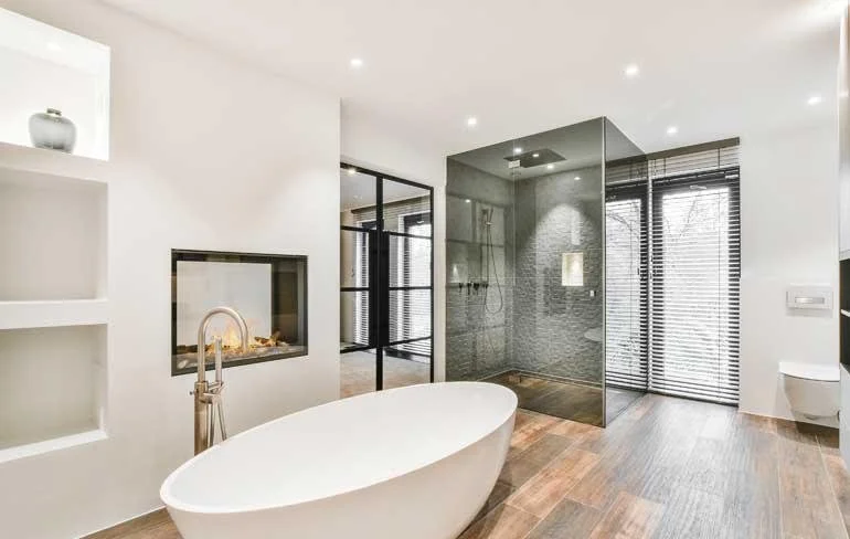 Modern bathroom with freestanding bathtub, glass-enclosed shower, and minimal decor.