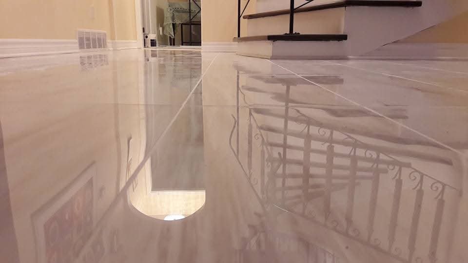 Reflected view of a staircase and railing on a polished tiled floor inside a house.