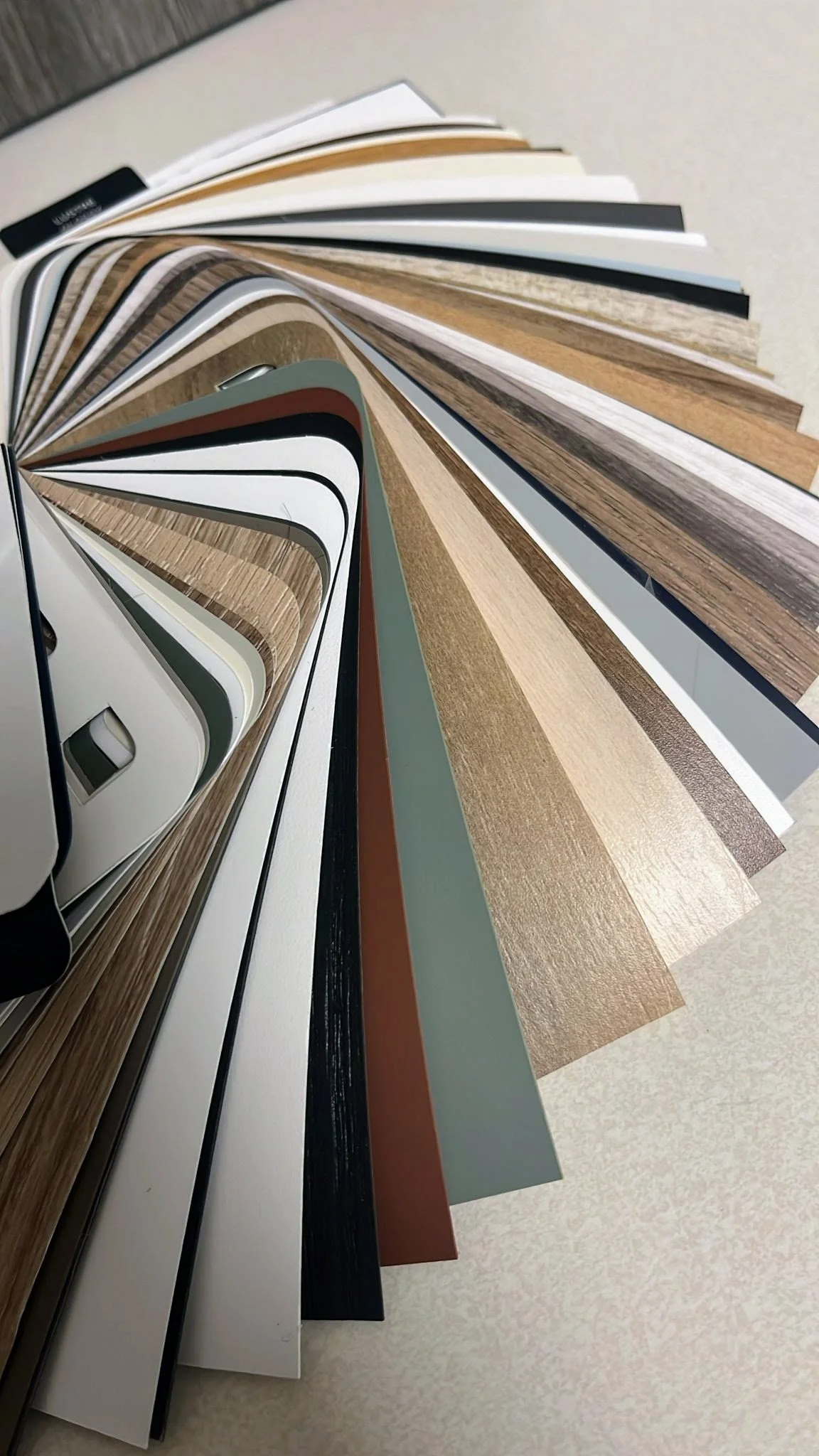 A fan deck of various interior and exterior wall paint and wallpaper samples fanned out on a surface.
