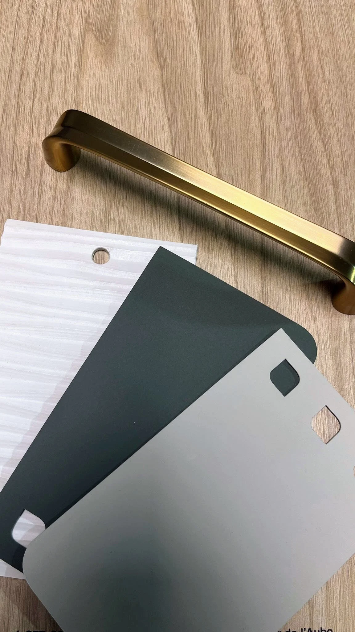 Brass drawer handle and metal sheets on wooden surface.