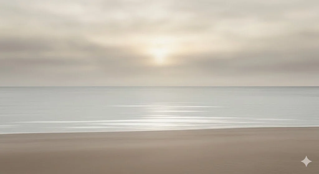 A calm beach scene with a sandy shoreline, gentle waves, and a cloudy sky at sunset or sunrise.
