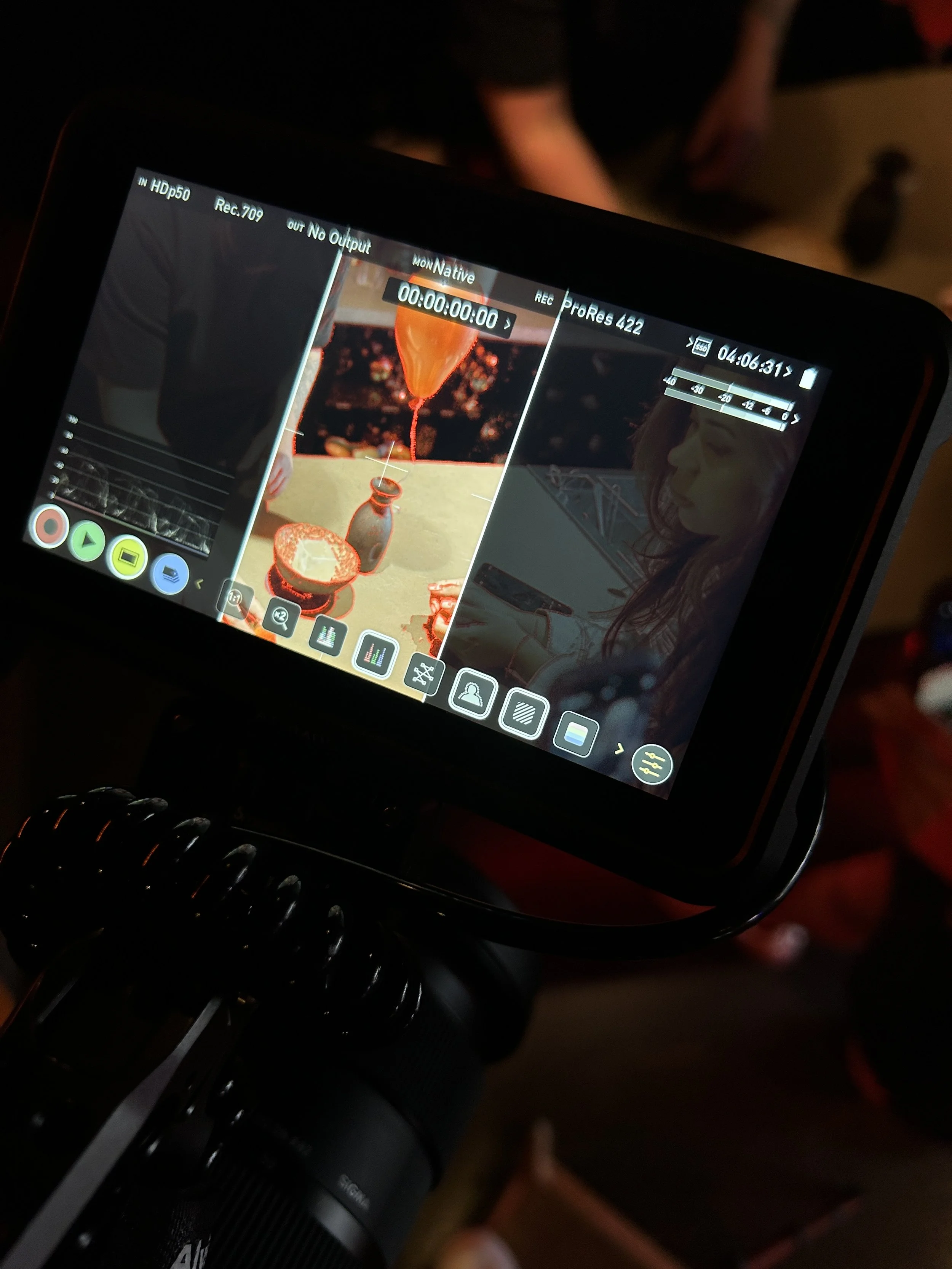 Een cameradisplay die opnames maakt van een tafel met een fles en een kom, met een persoon op de achtergrond.