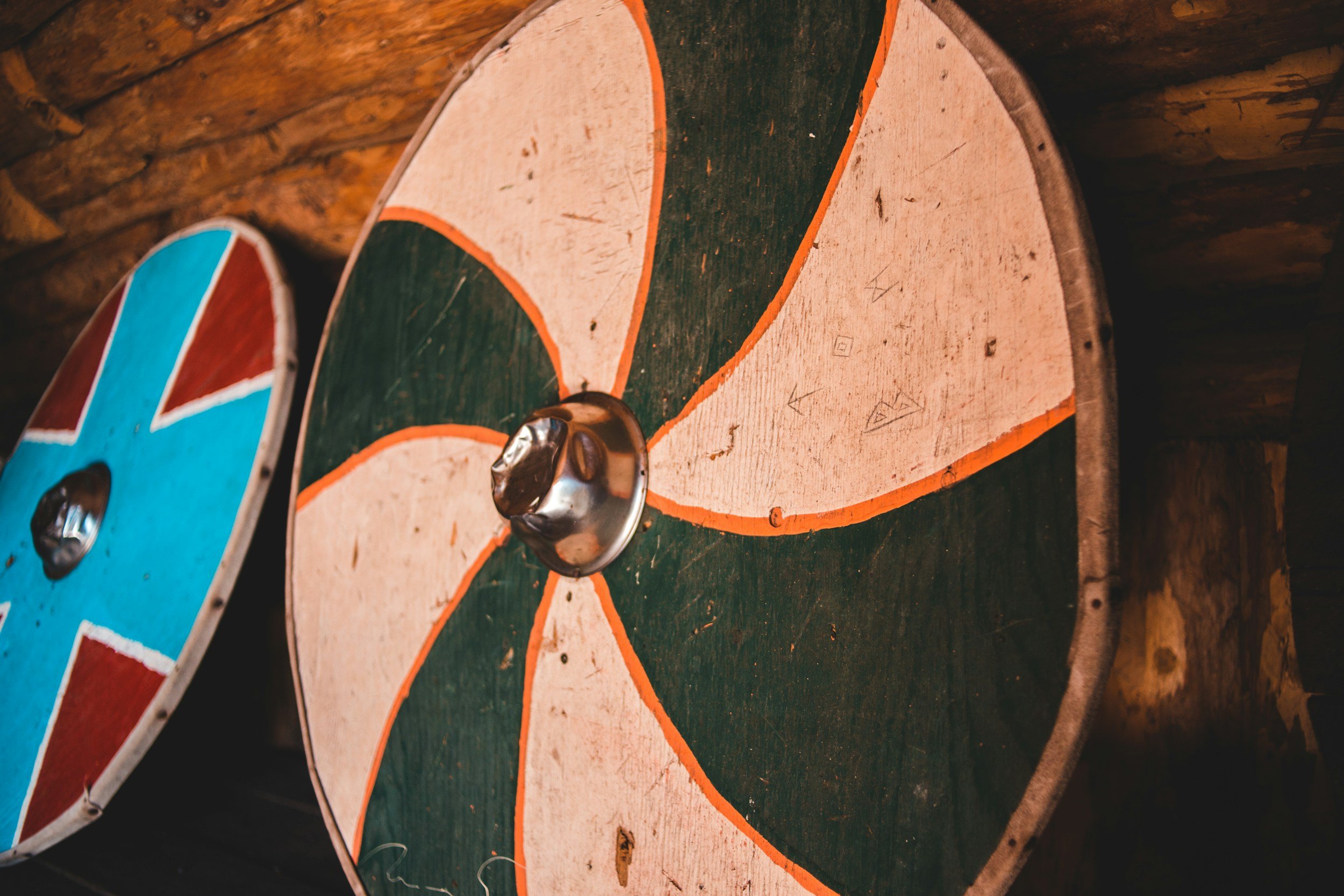 Close-up of two vintage wooden shuffleboard pucks with metal handles, resting on a dark wooden surface.