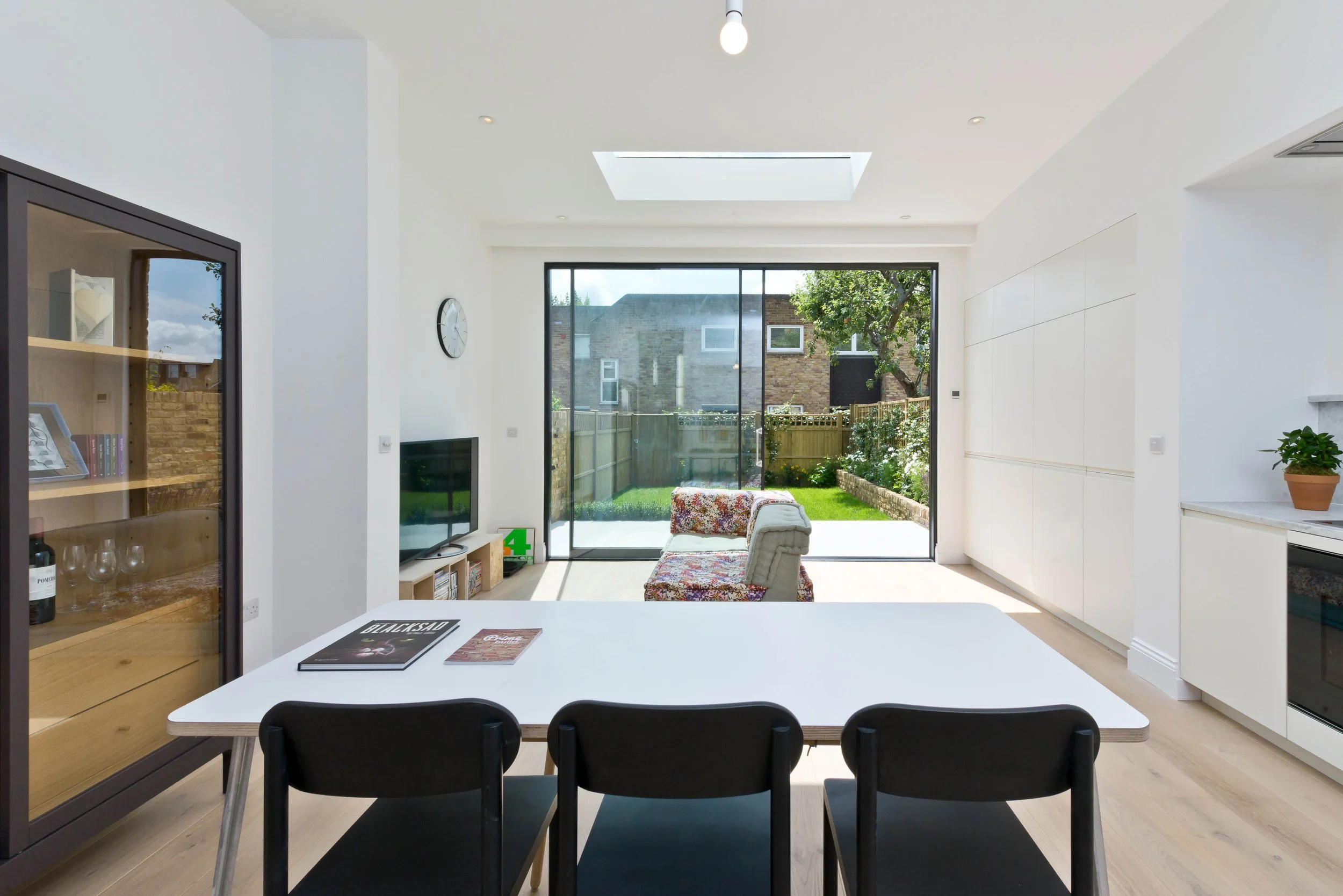 Modern open-concept living and dining area with a view of a backyard garden through large sliding glass doors.