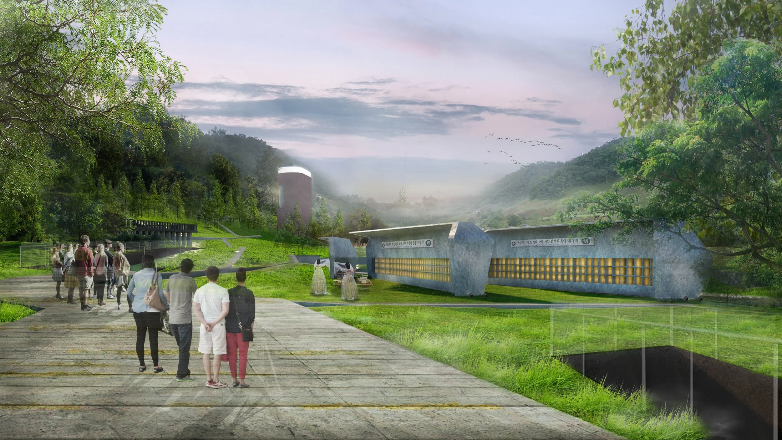 People walking on a pathway near modern buildings, with large green trees and hills in the background, under a cloudy sky.