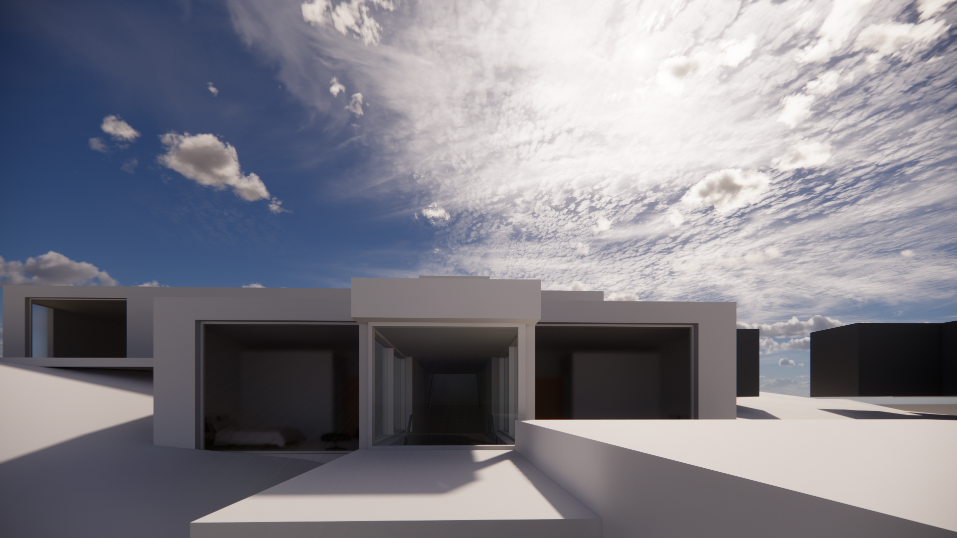 Modern white building with large windows and an open central passageway under a partly cloudy sky with the sun shining.