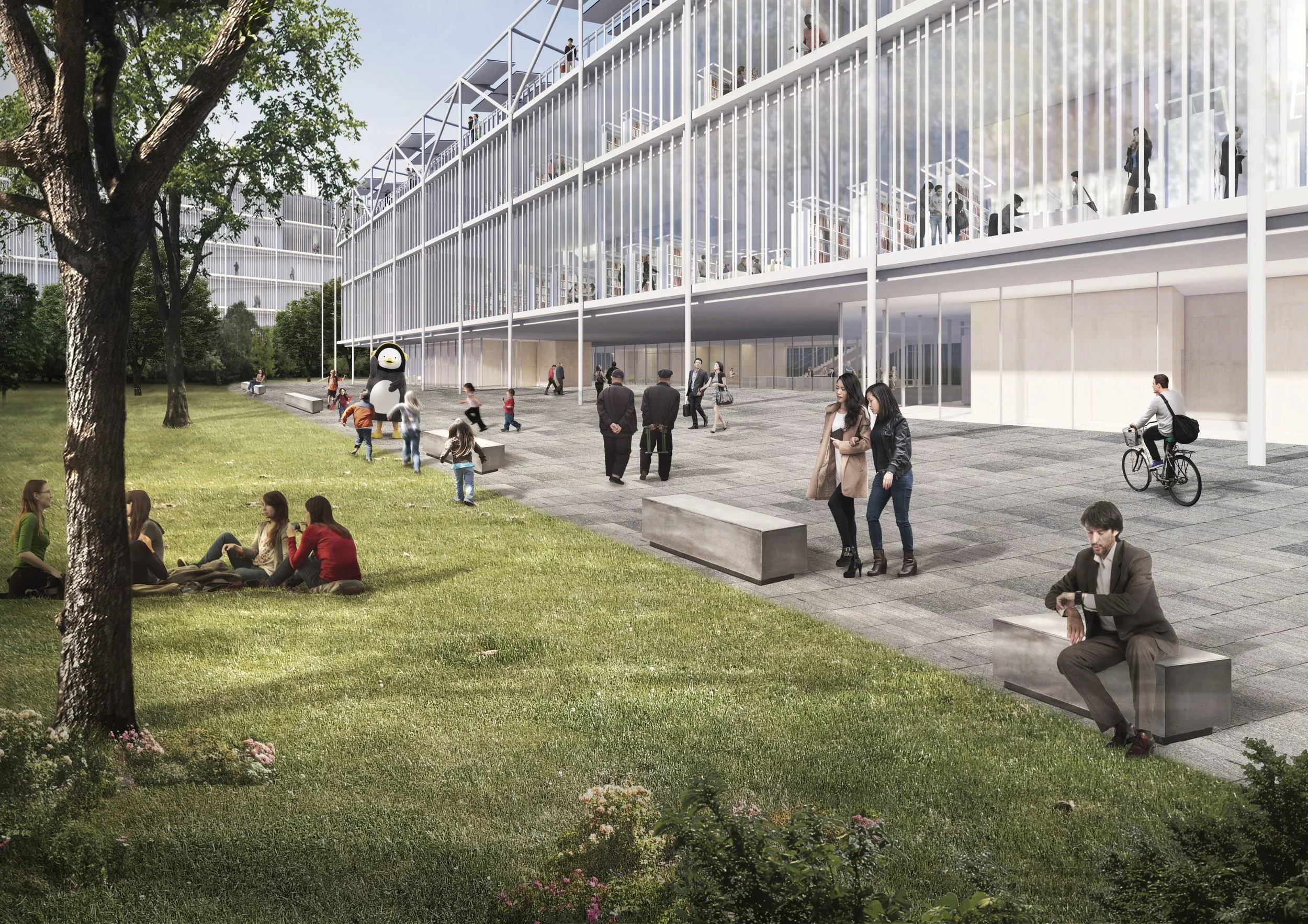People sitting on the grass and benches in front of a modern glass building with multiple levels and outdoor walkways. Some children are playing near a penguin mascot figure, while others walk or cycle nearby. The scene is set on a sunny day with tre