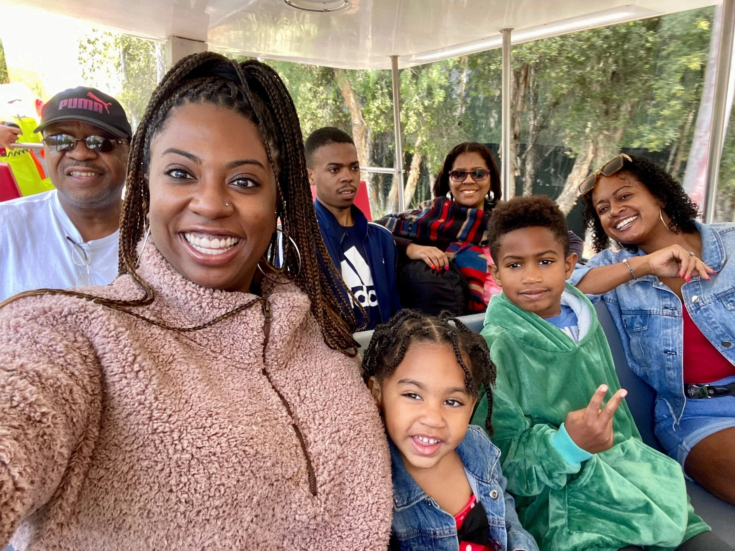 Gathered Well founder, Celia sits in the far right corner in a red shirt and blue jean jacket next to her son, niece, and sister holding the camera for a selfie. Behind her right shoulder is our father, followed by our brother and mother at Disney.