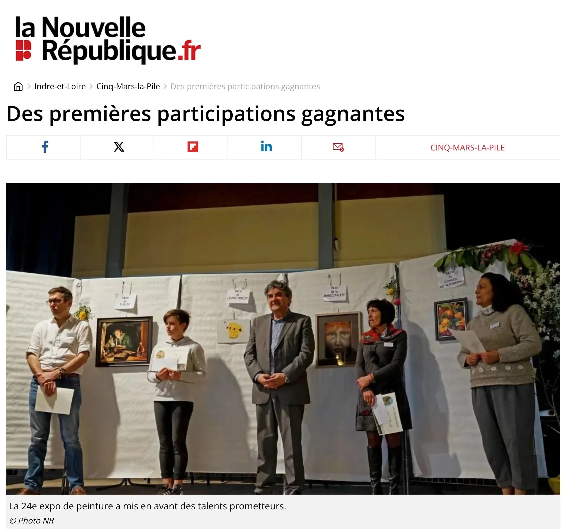 Groupe de cinq personnes debout lors d'une cérémonie ou expositions, avec des œuvres d'art exposées en arrière-plan, dans une salle d'événement.