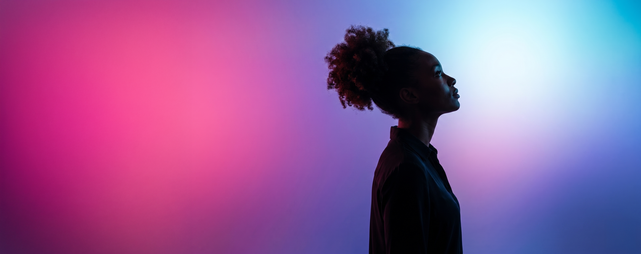 A silhouette of a woman with natural curly hair, looking to the right, against a background with vibrant gradient colors transitioning from pink to purple to blue.