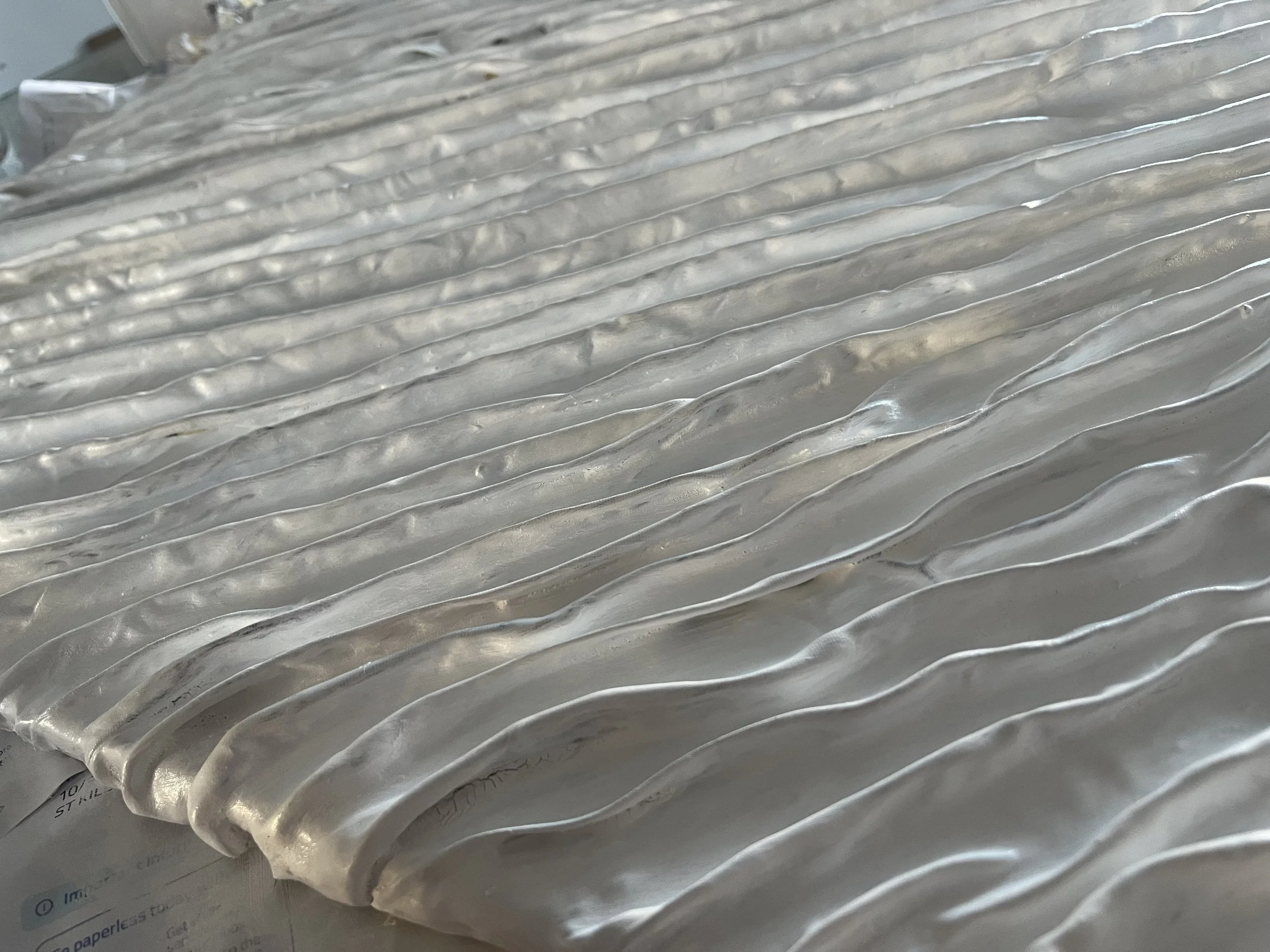 Close-up of a textured, shiny, wavy metal surface.