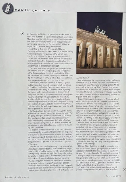 Photo of the Brandenburg Gate in Berlin, Germany during nighttime, illuminated with lighting, with flags flapping in the foreground.