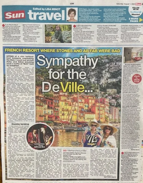 A newspaper page from Sun Travel section featuring an article about the French Riviera, specifically Villefranche and Cap-Ferrat. The article highlights the charming scenery, colorful buildings, and waterfront views. The main photo shows two women wi