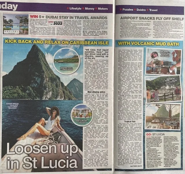 A newspaper spread featuring travel articles about St. Lucia, highlighting Caribbean island relaxation, volcanic mud baths, and sunset scenes, with images of a woman relaxing on a boat and scenic landscapes.