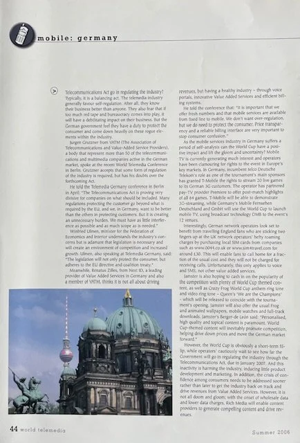 Close-up photo of a section of a printed magazine or journal article, including a small circular icon resembling a cellphone, with the text 'mobile: germany' beside it, and a blurry image of a historic building with domed roof at the bottom.