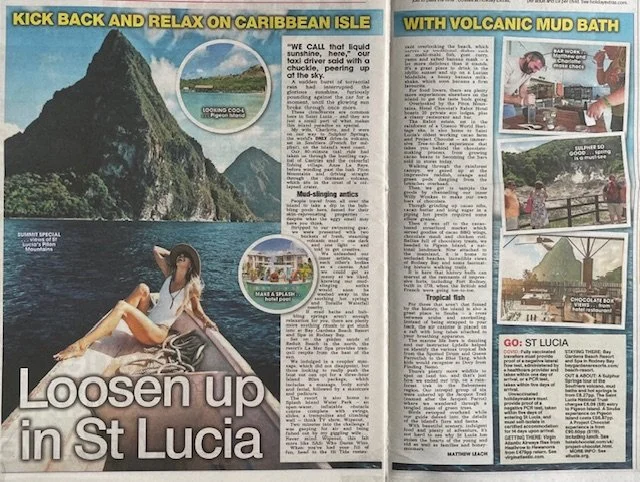 A magazine spread showcasing St. Lucia as a Caribbean travel destination. The left page features a large photo of a woman relaxing outdoors with a mountain and water in the background, and a subtitle 'Loosen up in St Lucia'. Smaller images depict a scenic mountain, a boat trip, and a pool. The right page contains articles about St. Lucia's attractions, including volcanic mud baths, tropical fish, and local activities, with additional images of mud baths, tropical fish, and a chocolate bar.
