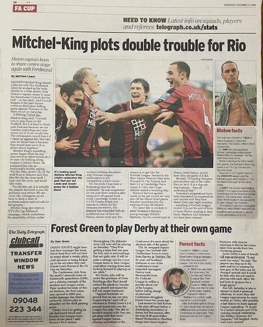 Photograph of soccer players in red and black uniforms celebrating on a soccer field, with one player extending his hand to another. An inset image shows a man in a green jacket. The headline reads 'Mitchel-King plots double trouble for Rio'; other a