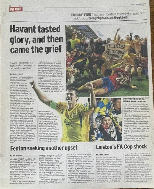 Photograph of a football team celebrating on the field, with fans and players holding a banner, and a young player in a yellow jersey smiling and raising his arms.