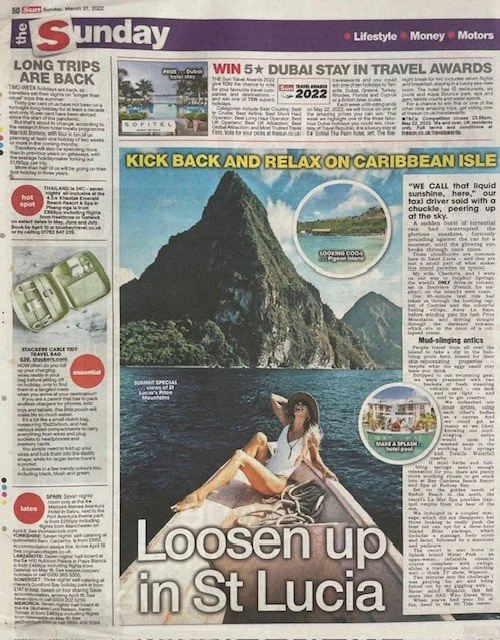 Newspaper page featuring travel article about St. Lucia, with a large photo of a woman relaxing in a boat near a prominent mountain and smaller inset images of beaches and resorts.