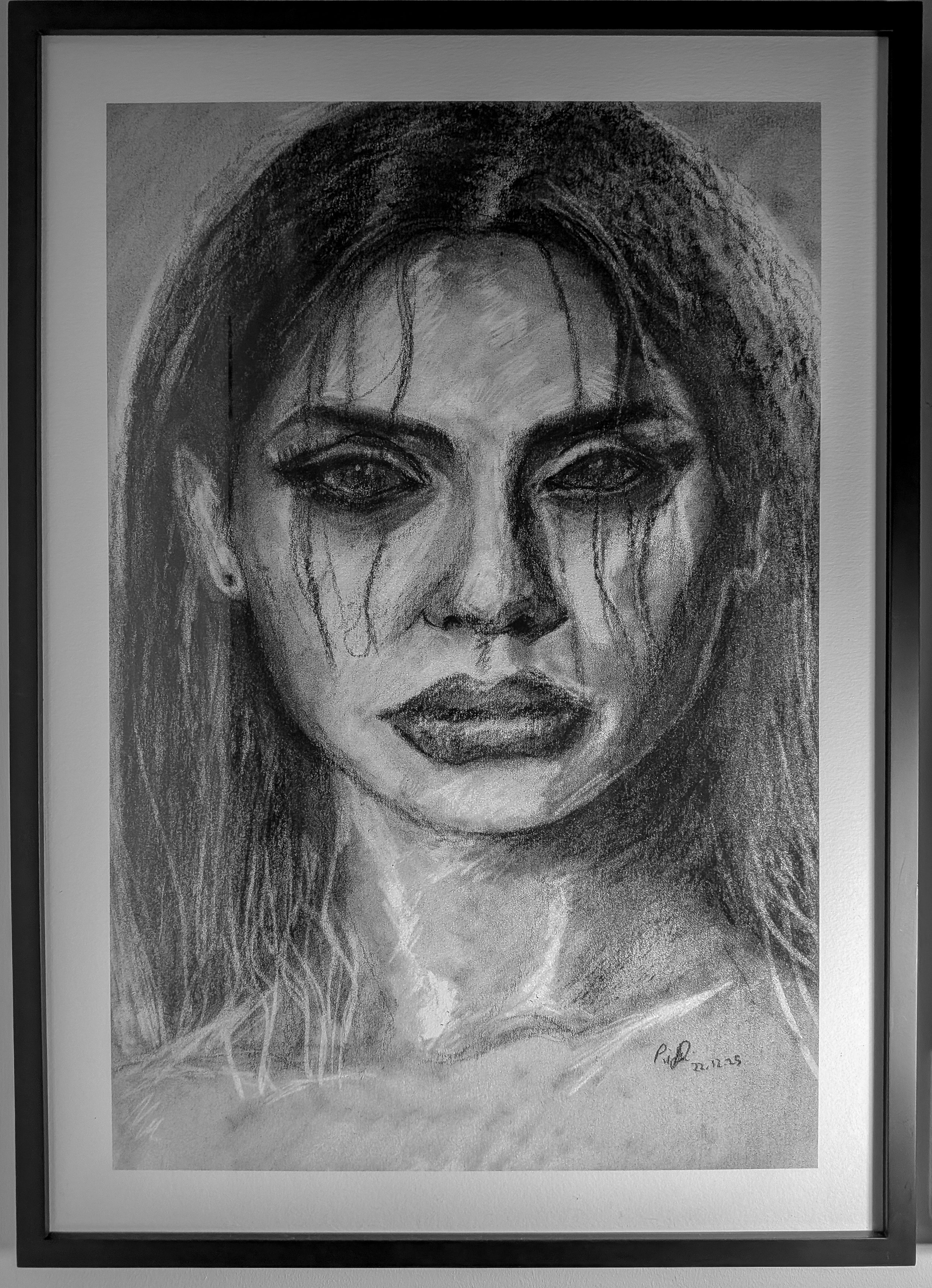 Black and white fine art print of a woman with long hair, dark eyes, and makeup, with tears coming down her face, in a black frame.