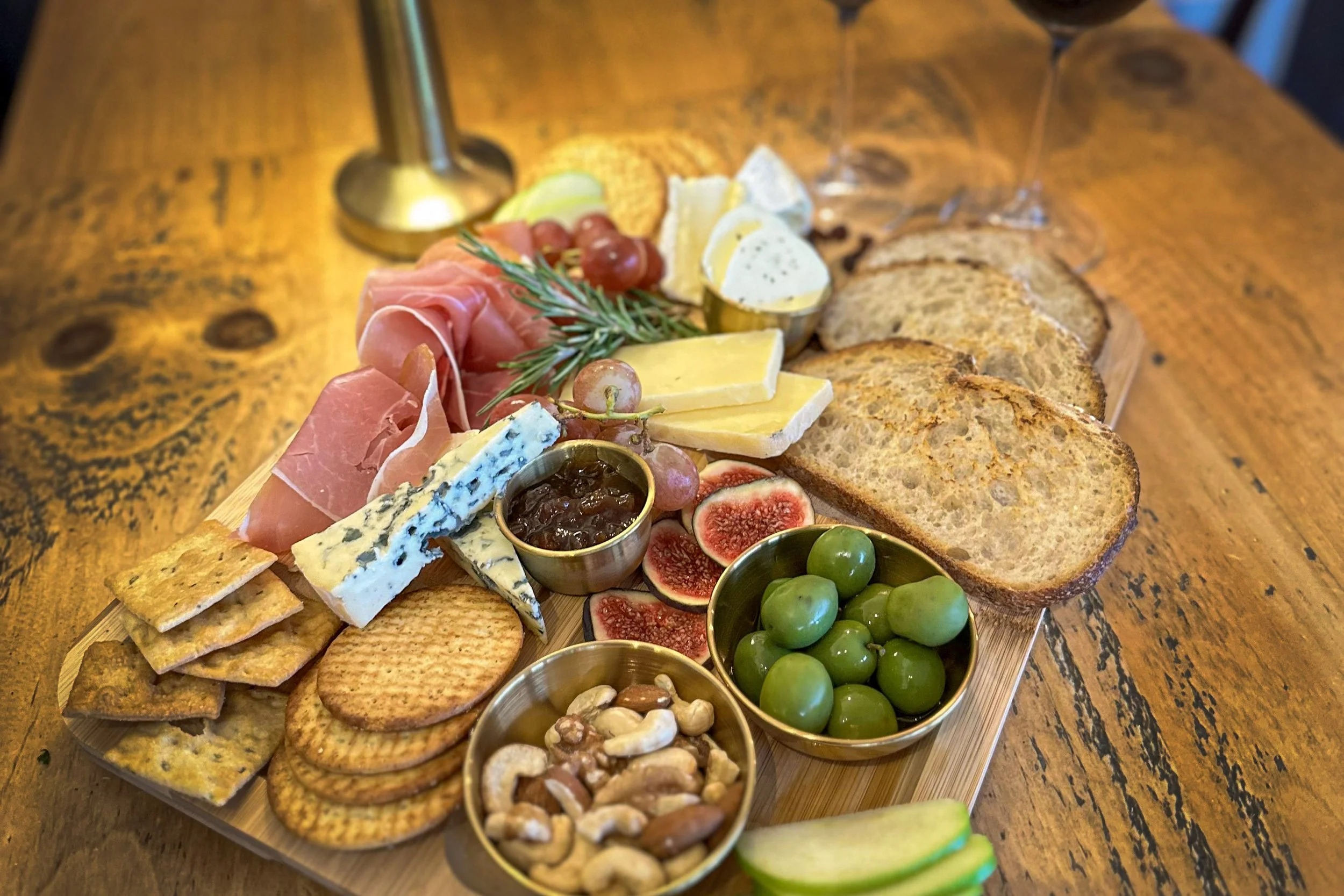 A charcuterie board with cheese, nuts, crackers, fruits, cured meats, and spreads at Bolo & Brew café Wine Bar in Horsley, Surrey