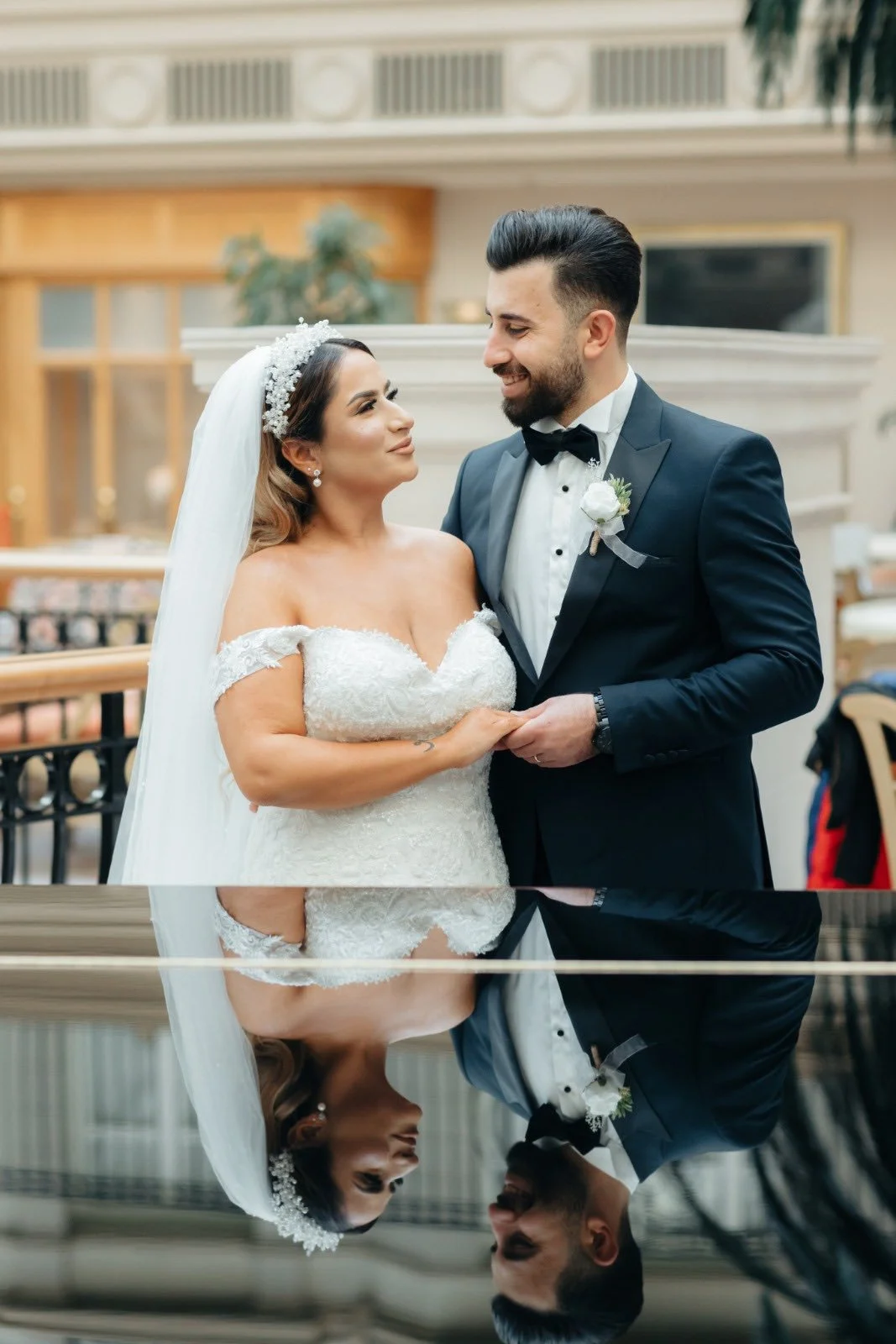 A bride and groom sharing a moment during their wedding ceremony inside a grand venue.
